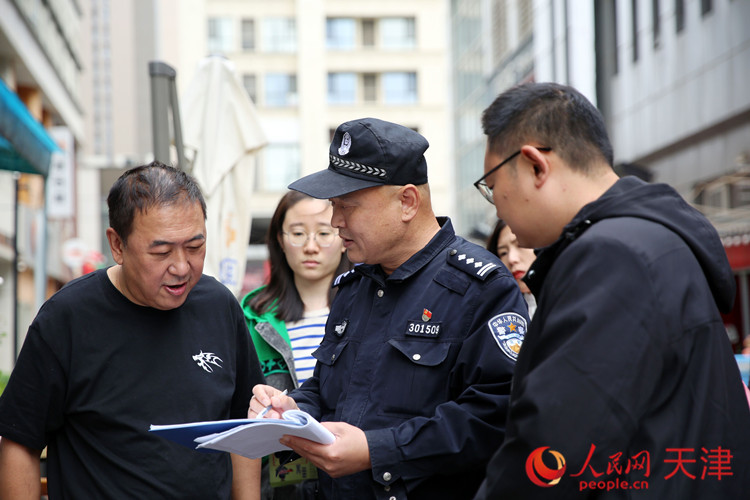 近日，天津公安南開分局體育中心派出所民警范星與社區(qū)網(wǎng)格員一起在時代奧城為商戶做防范宣傳。人民網(wǎng)記者 孫翼飛攝