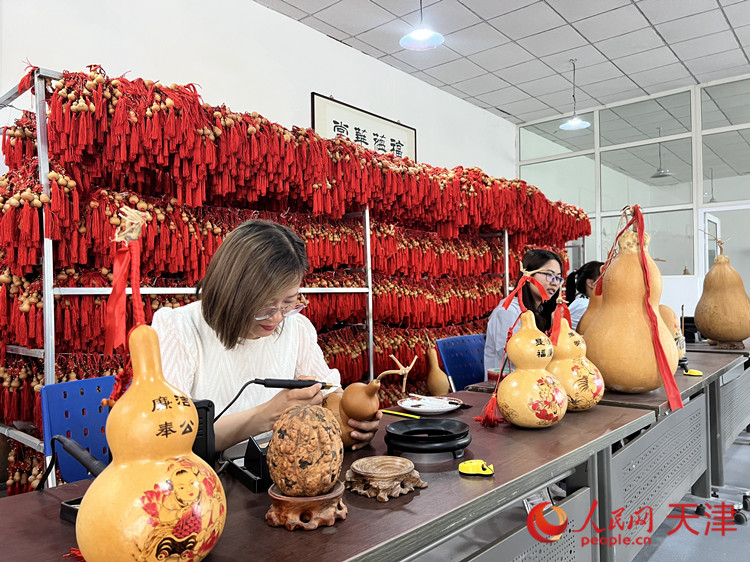 在大杜莊村葫蘆加工體驗館，朱娜正在教學生們在葫蘆上創(chuàng)作電烙畫。人民網(wǎng)記者 孫翼飛攝