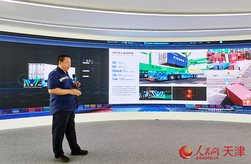 天津港第二集裝箱碼頭公司副總經(jīng)理高延輝為調(diào)研采訪團(tuán)介紹ART無人自動駕駛。人民網(wǎng) 郭維瑾攝