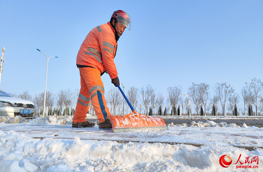 環(huán)衛(wèi)工人手持推雪板，清掃便道上的積雪，守護(hù)市民出行“平安路”。人民網(wǎng) 郭維瑾攝