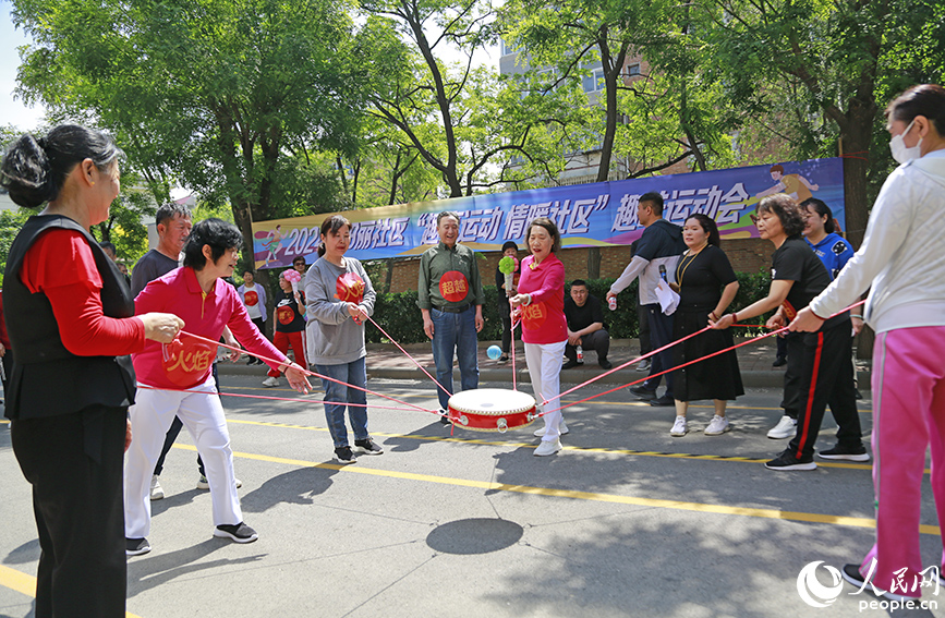 “同心鼓”項(xiàng)目中，隊(duì)員牽拉一根固定在鼓邊的繩子，齊心協(xié)力將鼓面上的球顛起。人民網(wǎng)記者 崔新耀攝